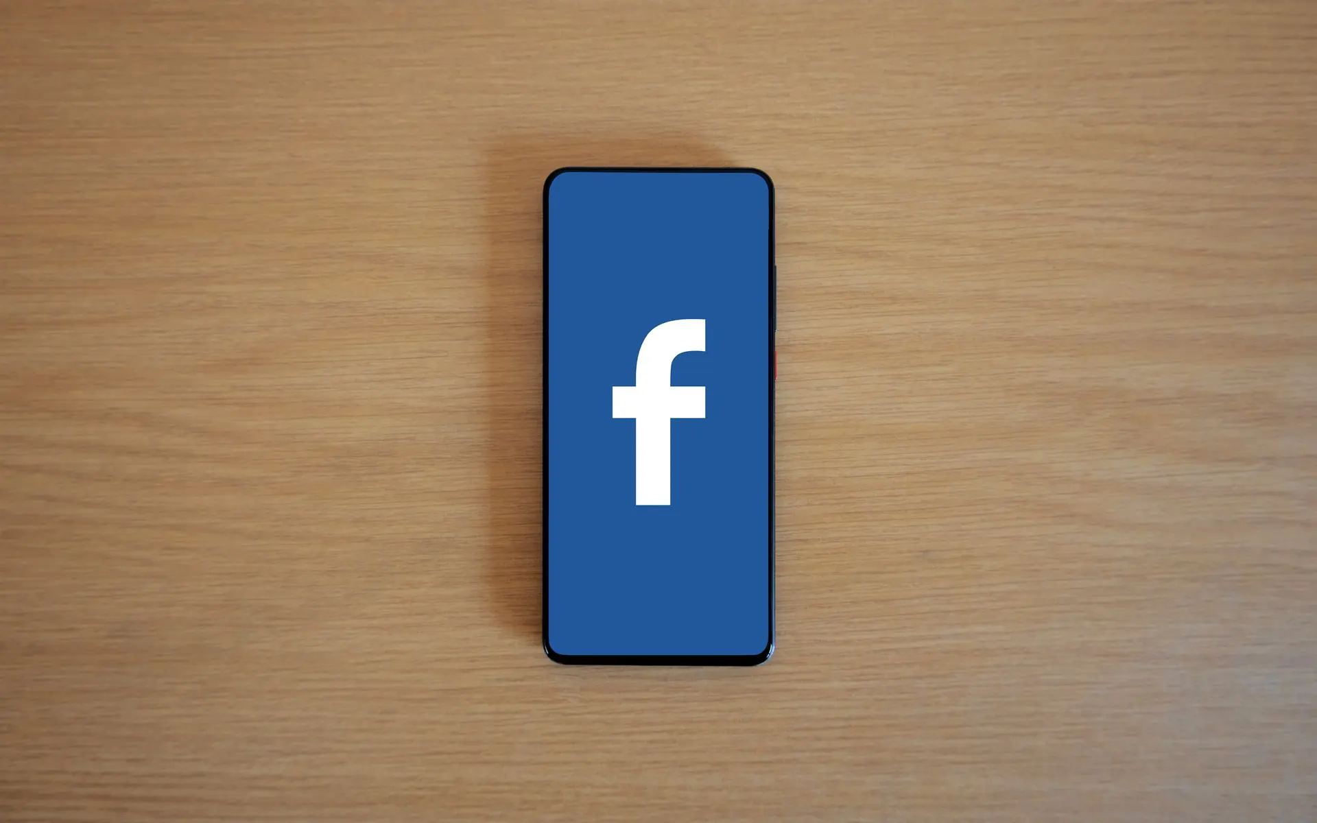 Facebook logo on a smartphone screen lying on a desk.