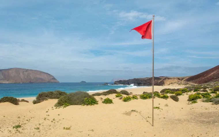Red flag flying on a beach.