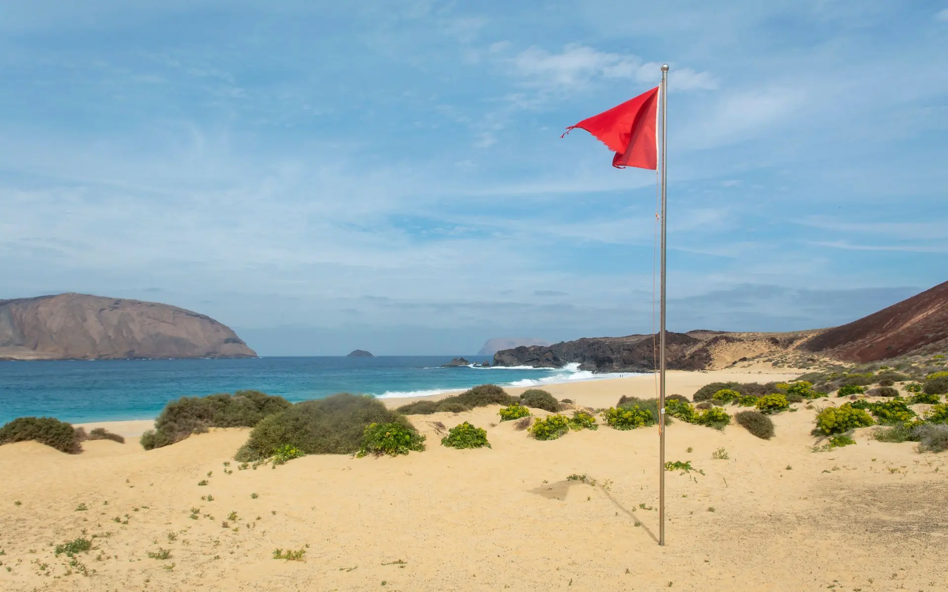 Red flag flying on a beach.