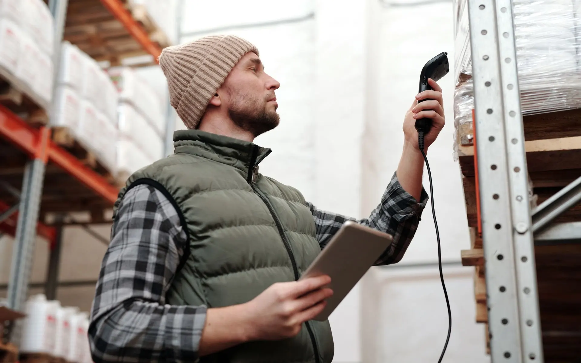 Warehouse worker scanning stock with a barcode scanner and tablet.