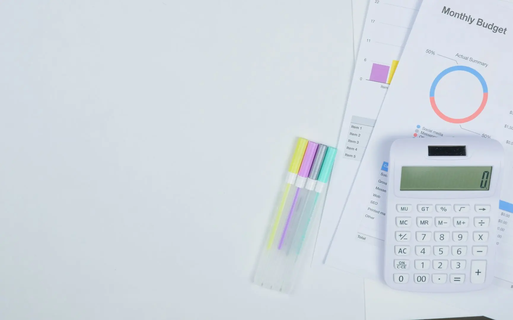 Budget worksheet with a calculator and highlighters on a desk.