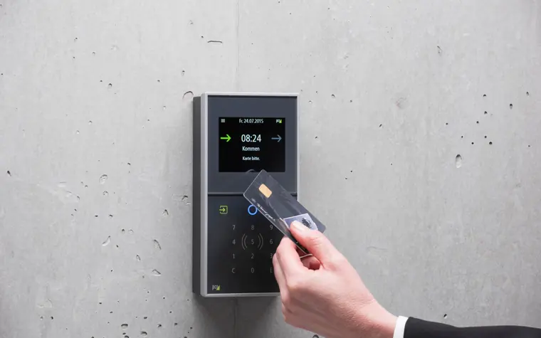 Hand holding an access card over an entry reader.