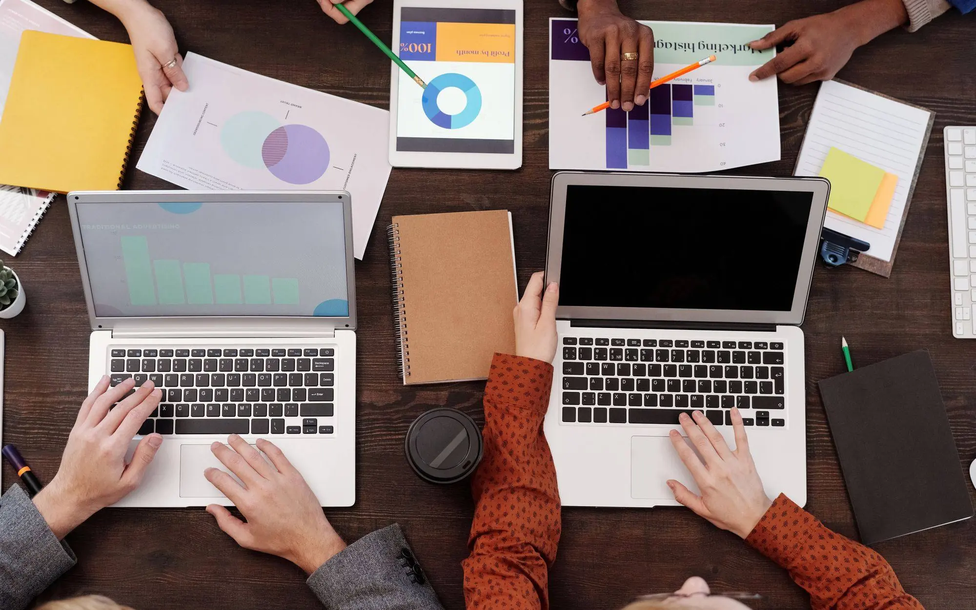 Group of people reviewing graphs and pie charts on a table.