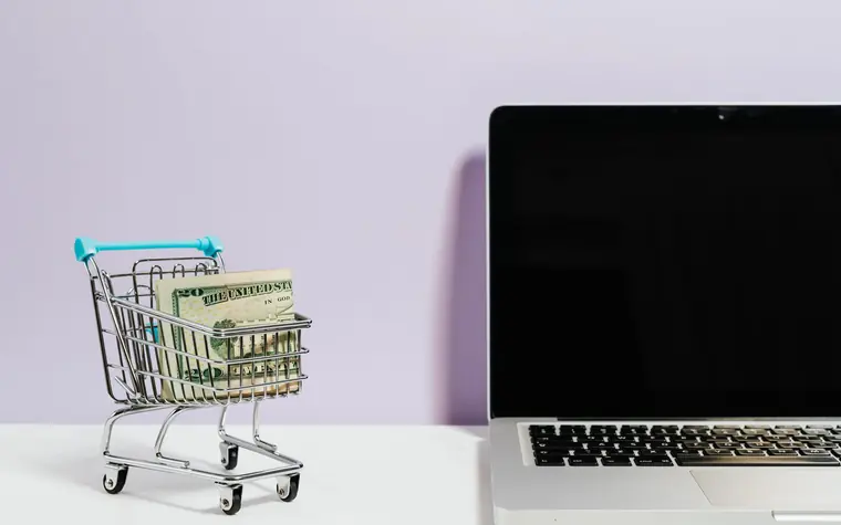 Shopping cart beside a laptop.