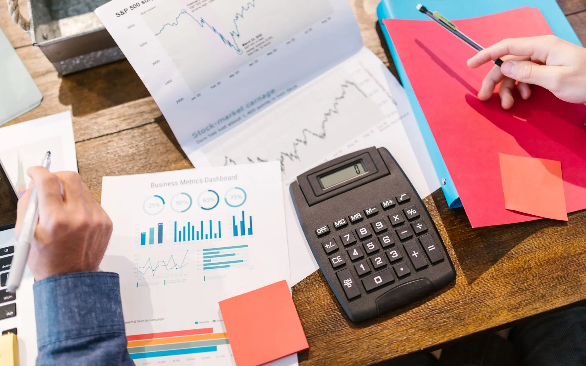 Financial documents, calculator and notebook on a desk.