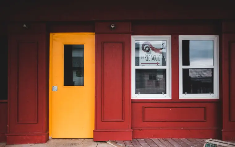 Exterior of cafe with red walls and yellow door.