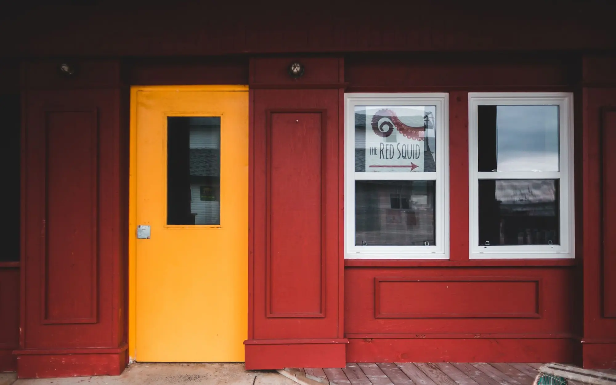 Exterior of cafe with red walls and yellow door.