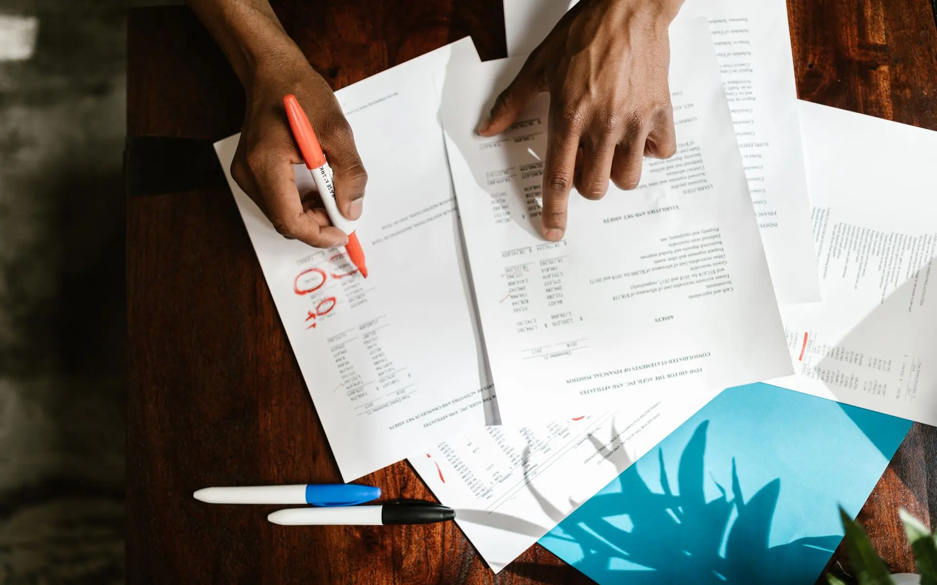 Overhead view of hands comparing several printed documents.