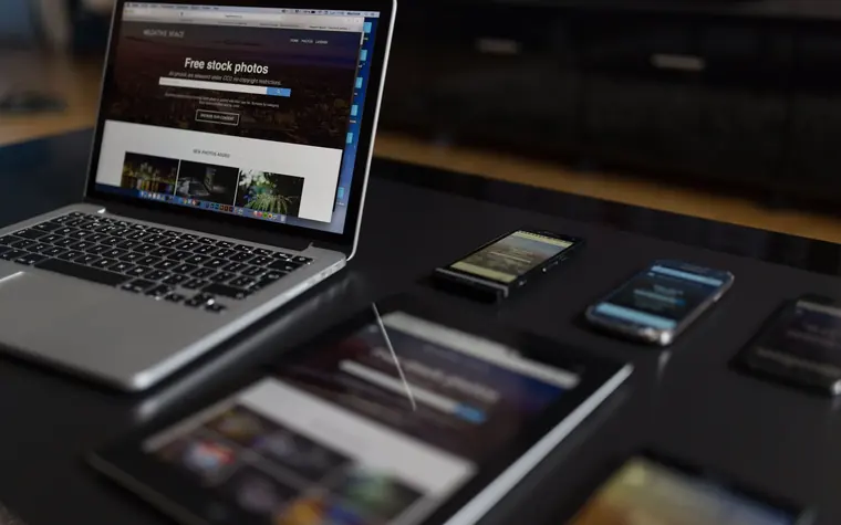 Laptop and several smartphones on a desk.
