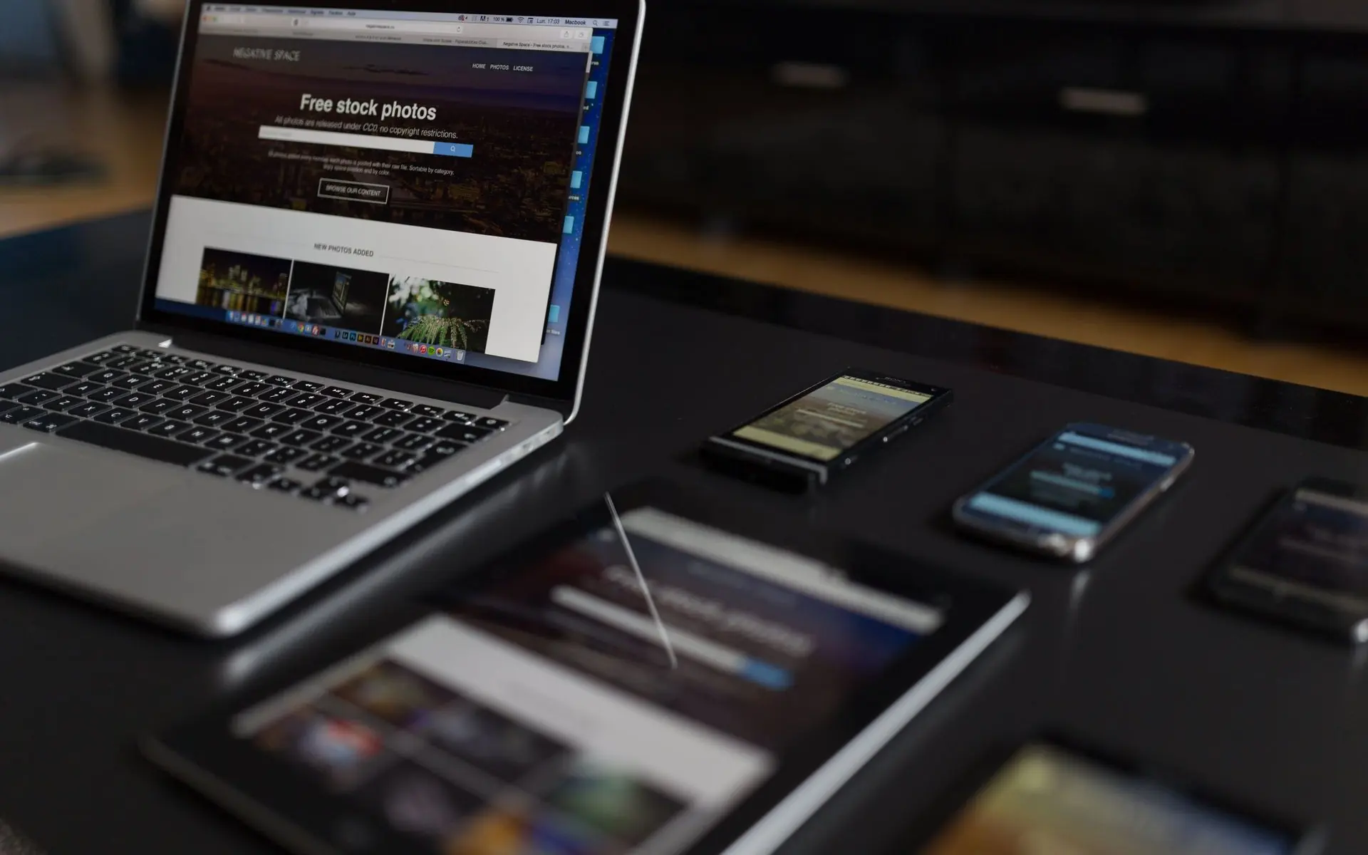 Laptop and several smartphones on a desk.