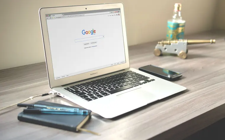 Google open on a laptop with a phone beside it.