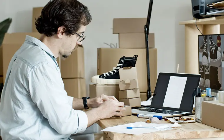 Store owner packing customer orders at a desk.