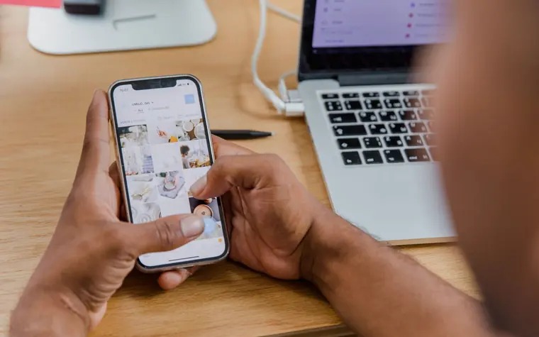 Person scheduling social media posts on a phone and laptop.