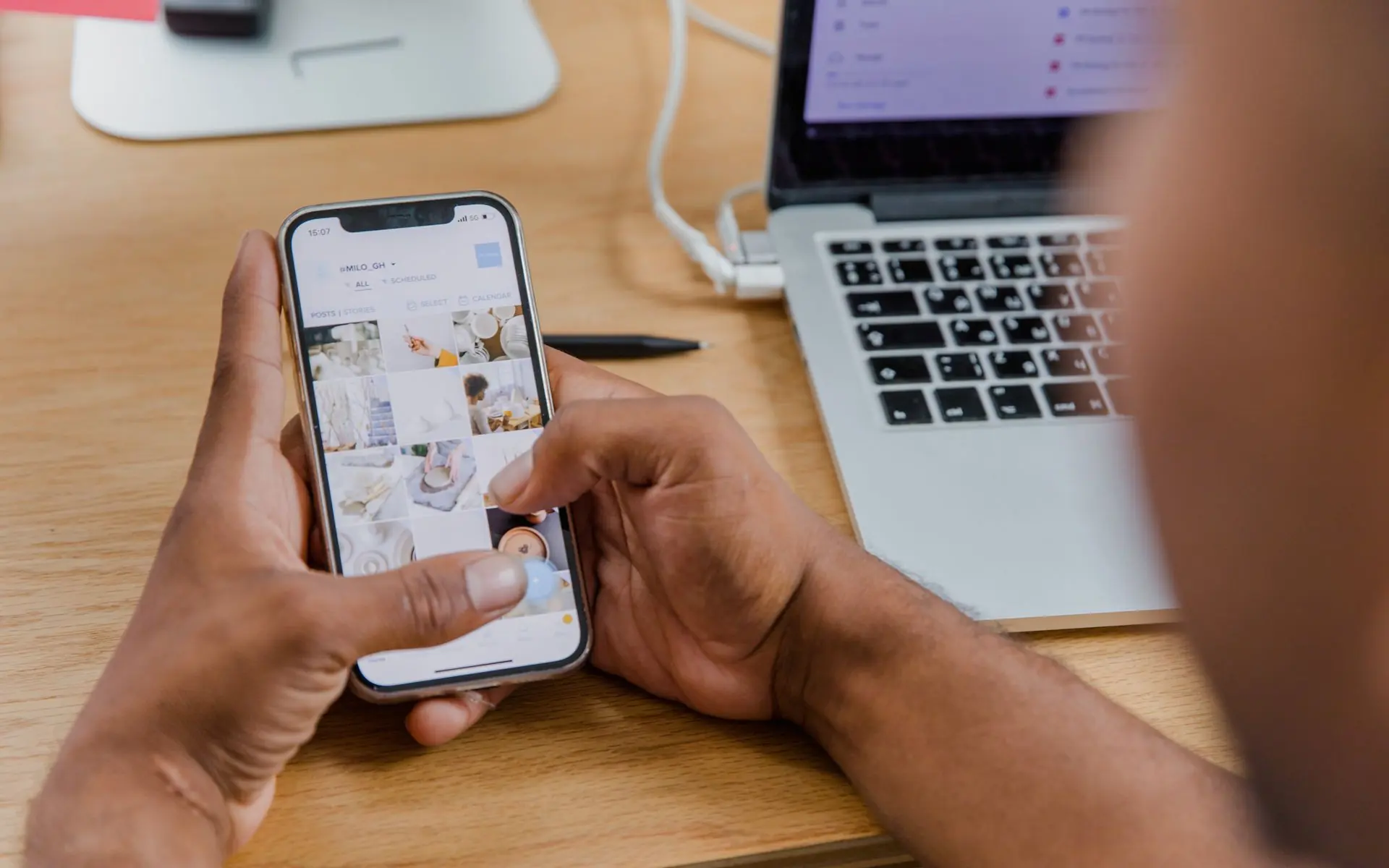 Person scheduling social media posts on a phone and laptop.