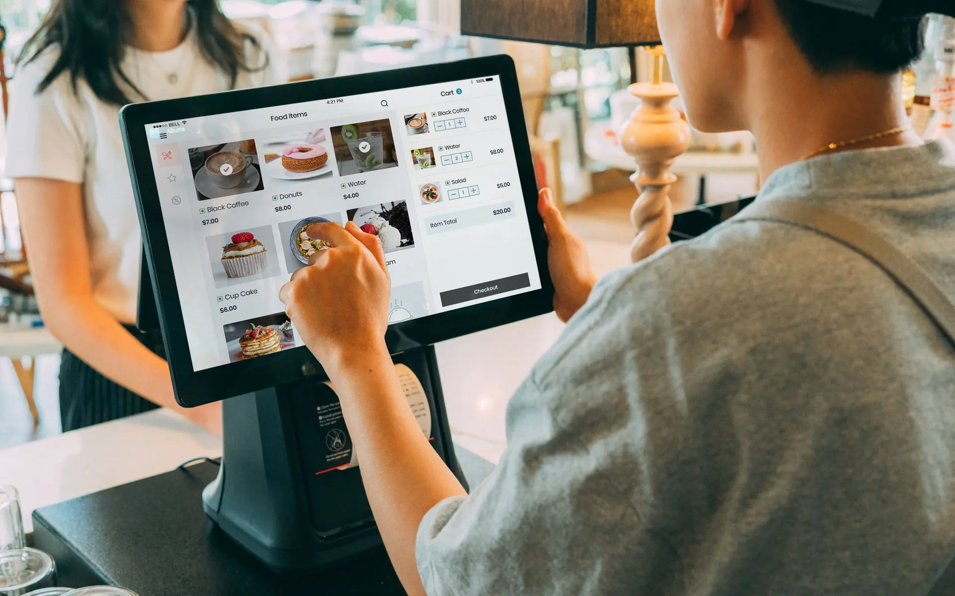 Cashier using a point of sale tablet at a counter.
