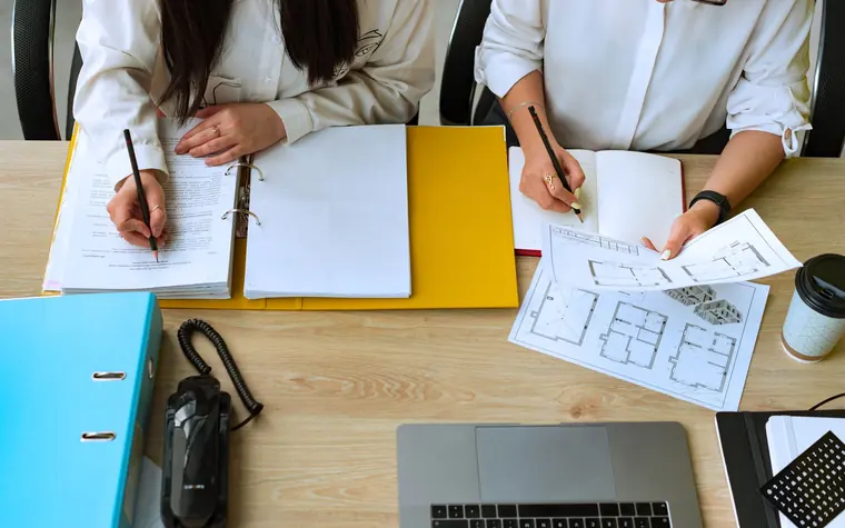 Colleagues working through structured documents at a desk.