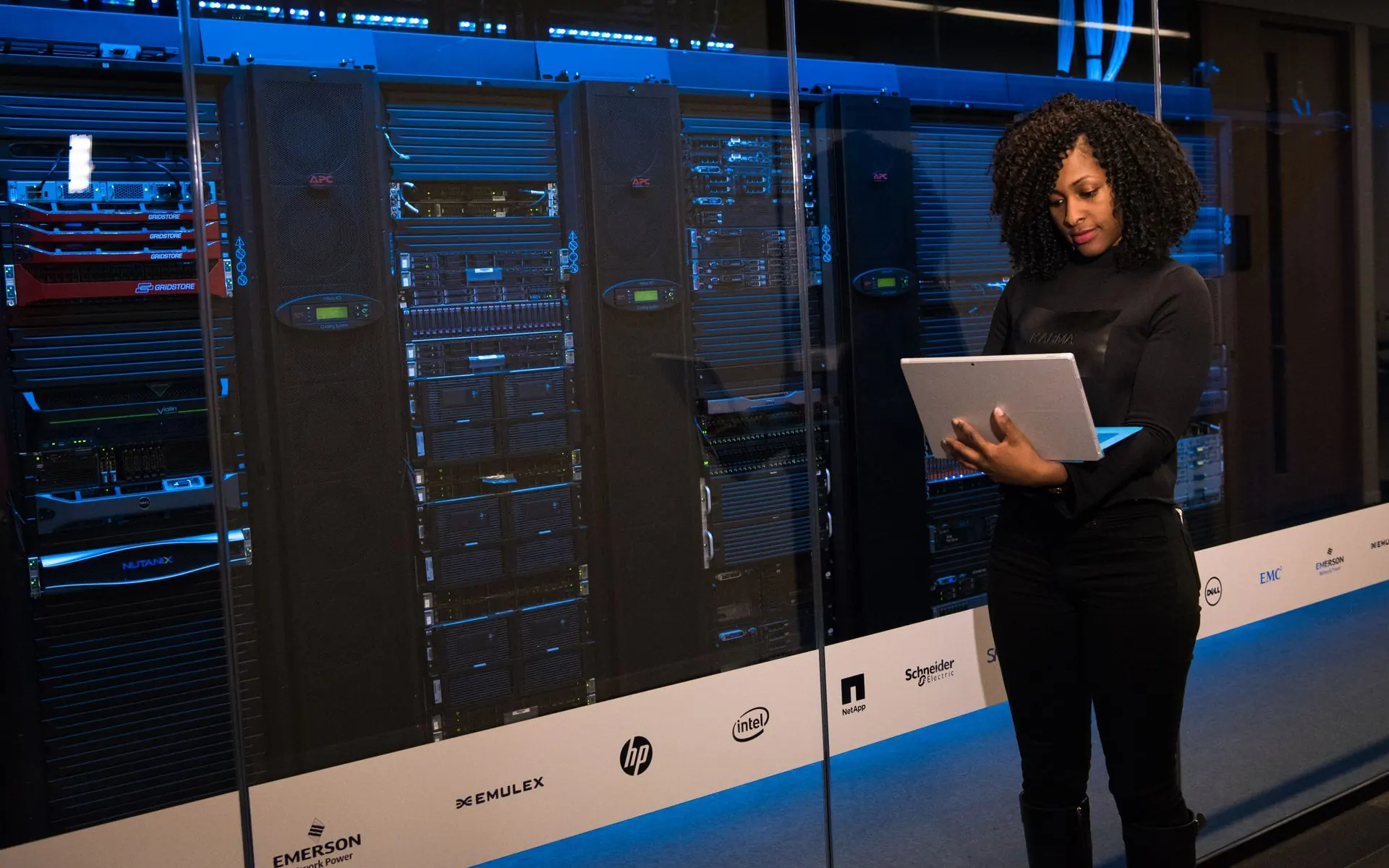 Engineer standing beside server racks with a laptop.
