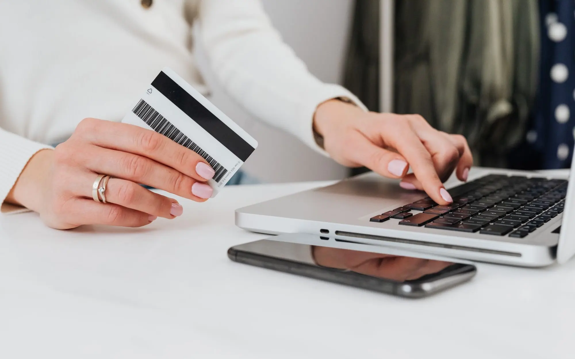 Person using a laptop and holding a credit card.