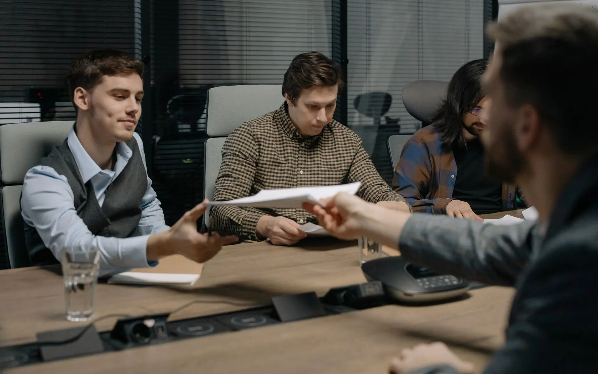 Documents being handed across a meeting table.