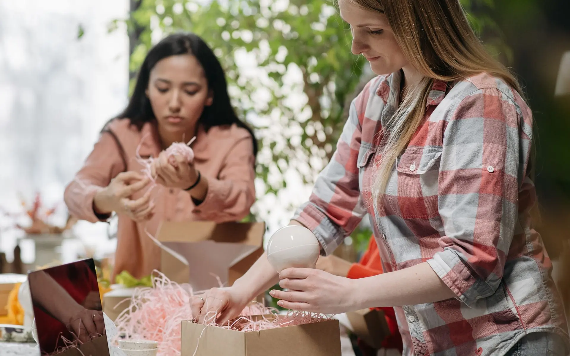 Two women packing orders into cardboard boxes.
