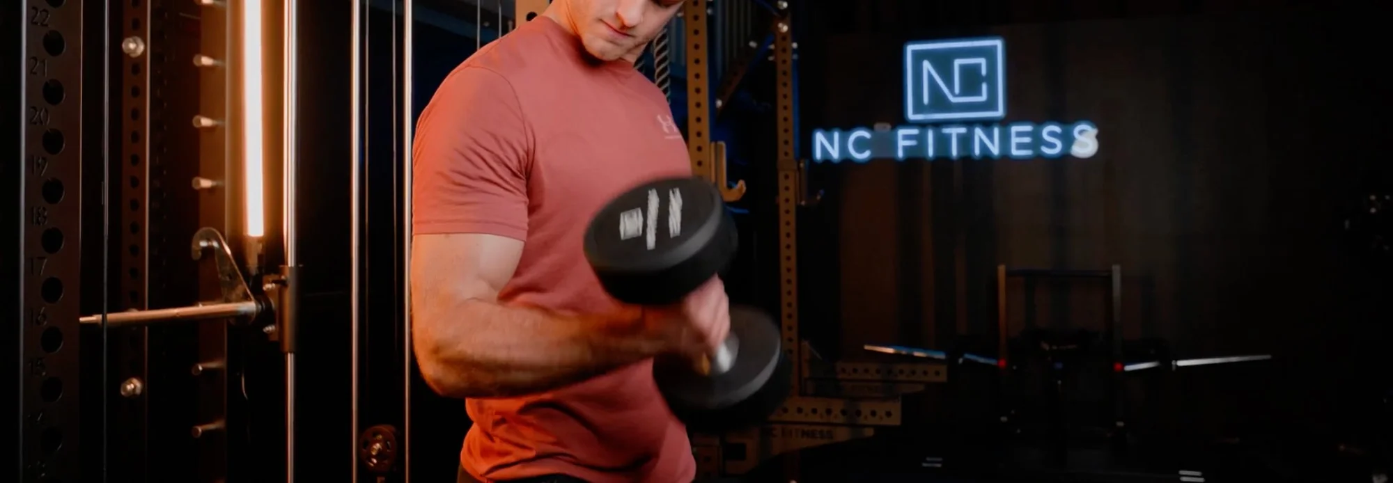 NC Fitness member training with dumbbell inside the branded gym.