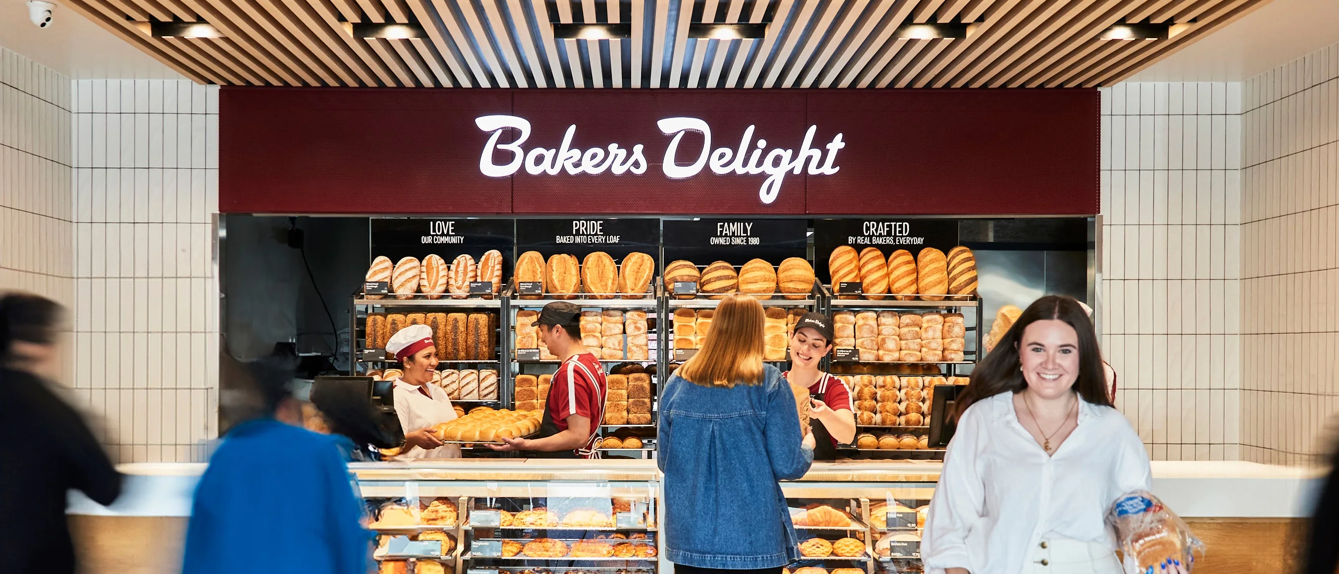 Customers at a Bakers Delight bakery counter.
