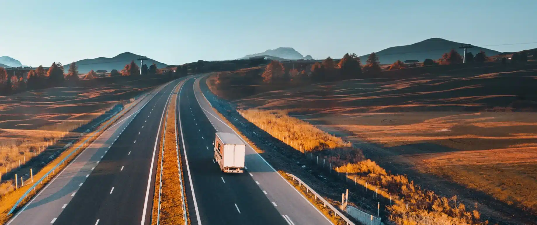 Truck travelling on a highway through a rural landscape.