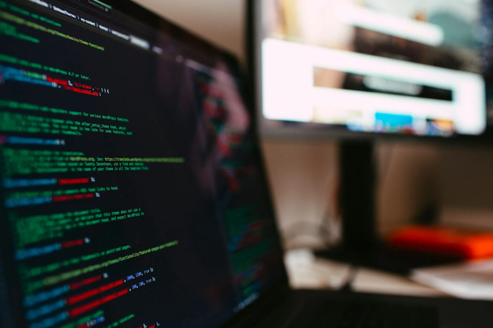 Website code on a developer's dual screen workstation.
