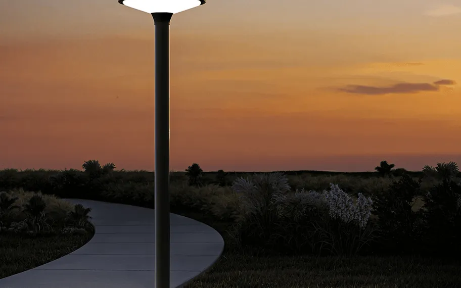 Outdoor lamp beside a garden path at sunset.