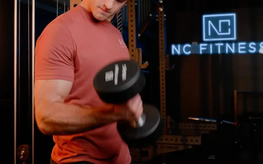 NC Fitness member training with dumbbell inside the branded gym.