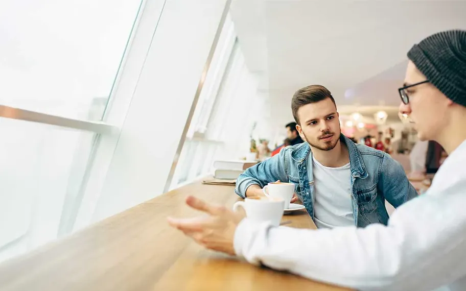 Two people talking at a window bench.