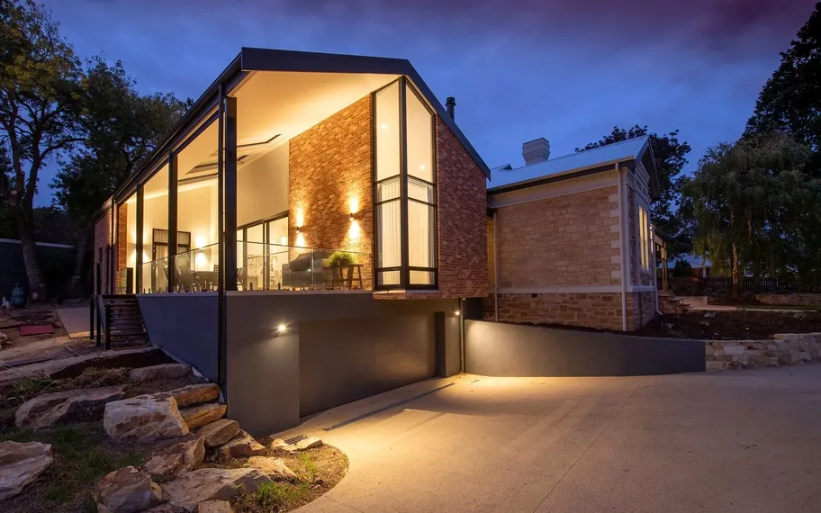 Modern house facade with warm lights glowing at dusk.