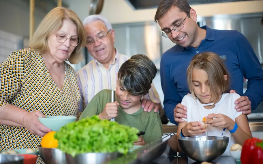 Multi-generational family preparing a meal together in the kitchen.