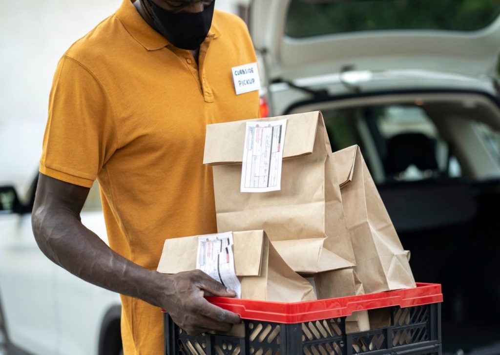 A delivery worker holds a crate of paper bags. How do you create the best online eCommerce experience everytime?