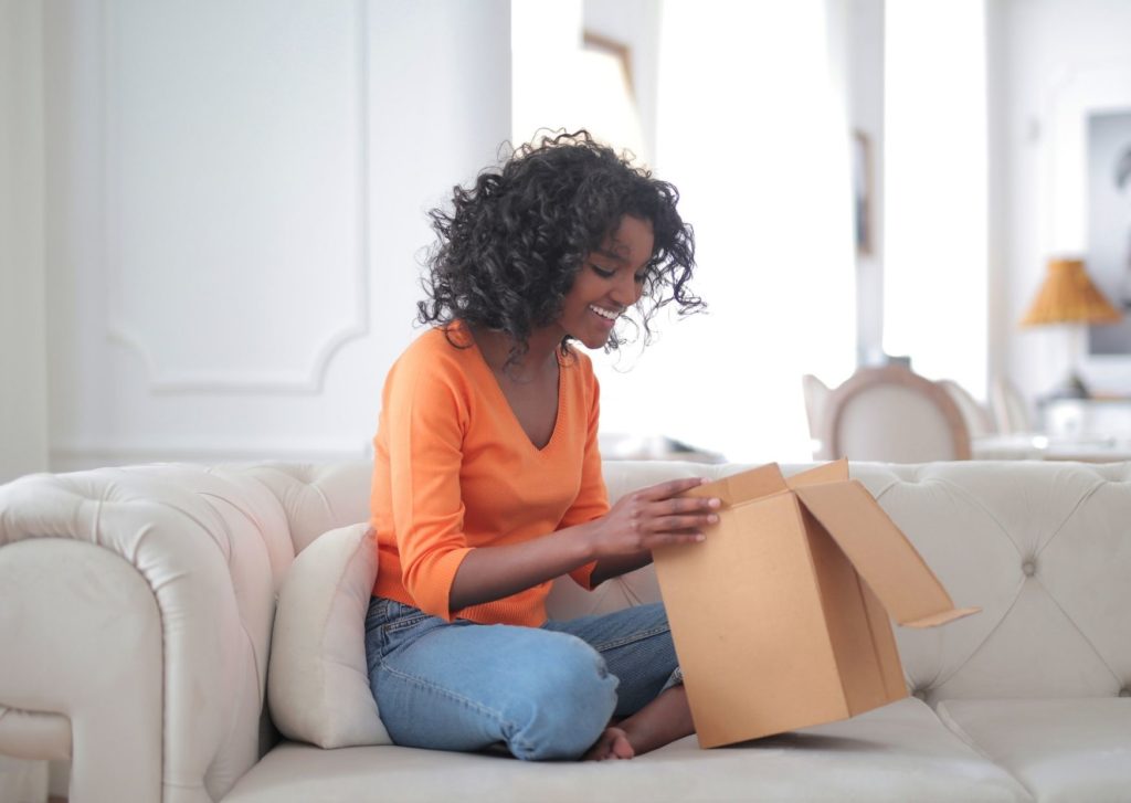 A woman sits on the sofa with a opened box. What are the new consumer trends and what do you need to watch out for?