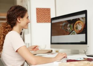 A woman uses a desktop computer. How to best impliment interaction design in your website.